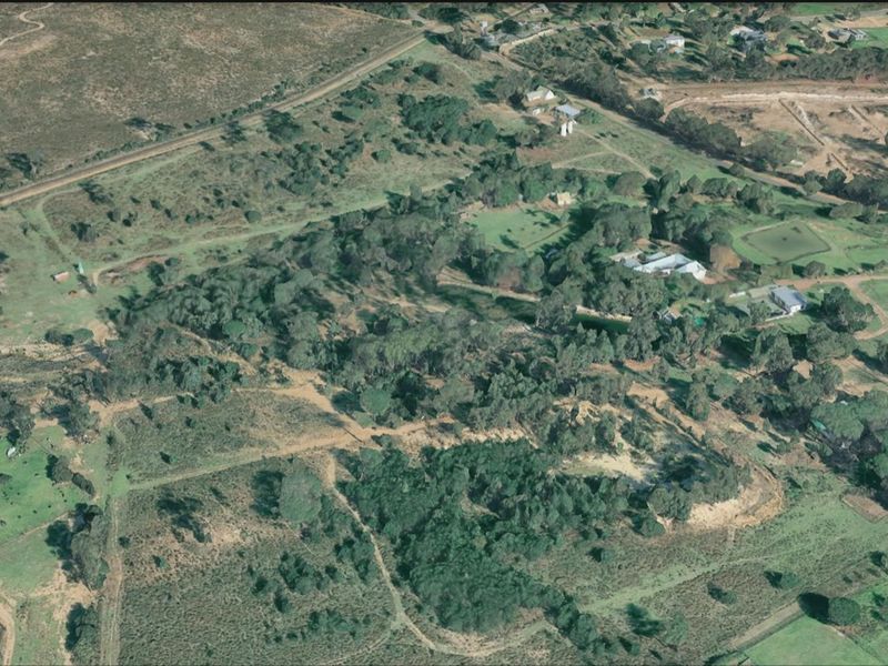 An aerial view of a large, undeveloped residential land parcel featuring established trees, natural vegetation, and surrounding rural landscape.