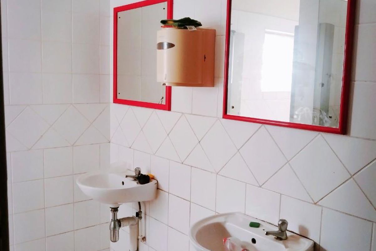 Commercial bathroom facility featuring dual wall-mounted ceramic basins, tiled walls, and vanity mirrors.