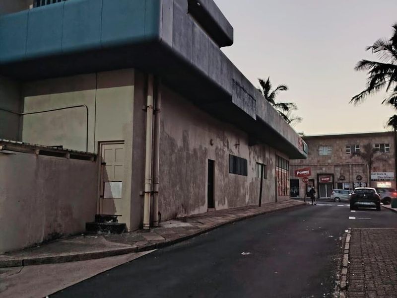 Street-level view of a commercial building facade showing weathered exterior finishes and architectural detailing along the roadside.