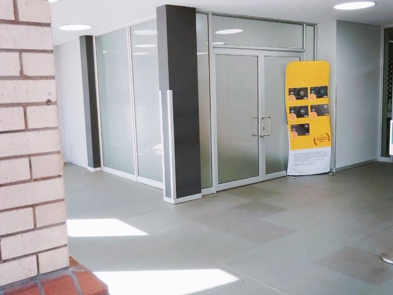 Modern commercial office entrance featuring glass partitioning, tiled flooring, and recessed ceiling lighting in a clean, professional environment.