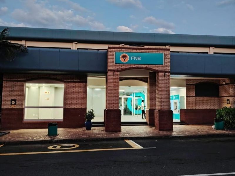 Front exterior view of a commercial bank branch featuring brick facade, large glass windows, and a prominent entrance.