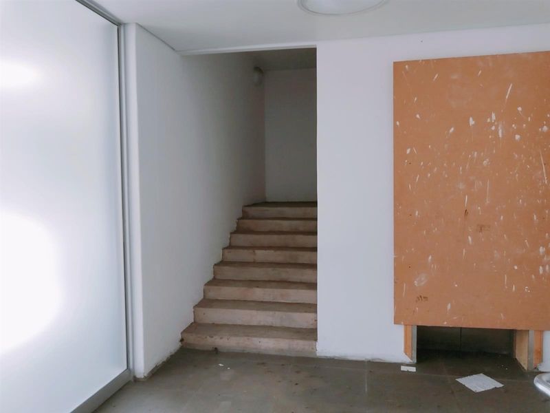 An interior view of a commercial space featuring a concrete staircase and unfinished wall paneling, presenting a blank canvas for renovation.