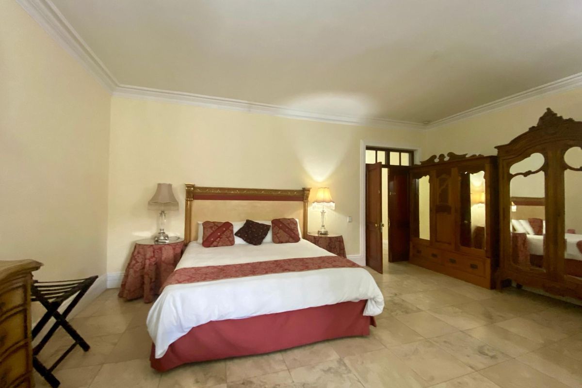 Spacious bedroom featuring light-toned stone flooring, crown molding, and a classic layout with ample space for bedroom furniture.