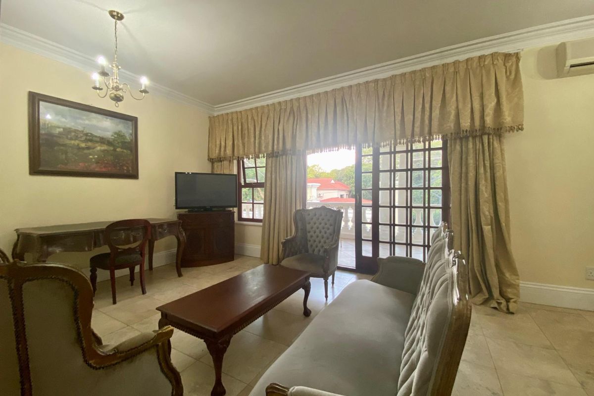 A spacious living room featuring tiled flooring, crown molding, and large glass sliding doors providing access to an outdoor balcony area.
