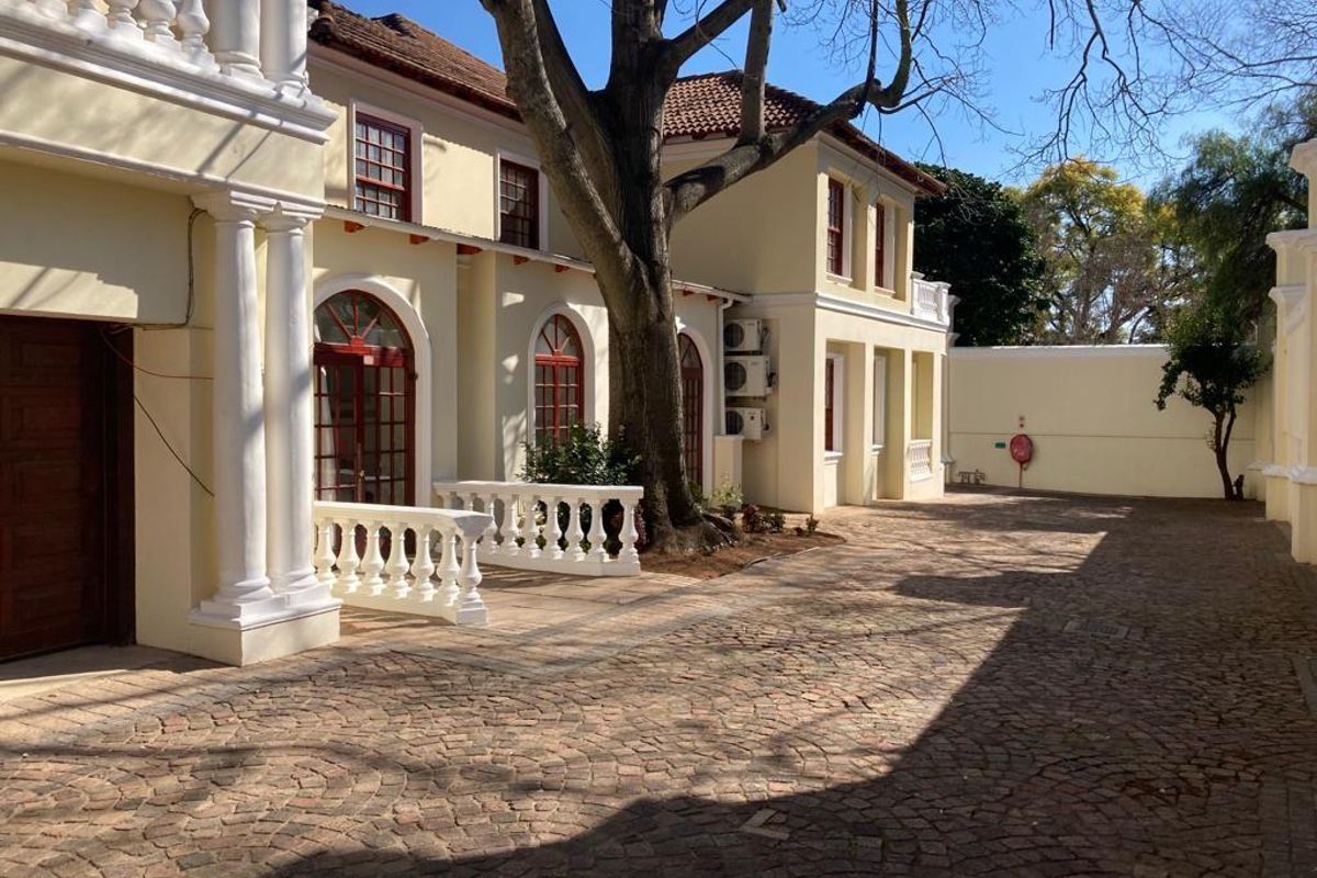 A view of the property's exterior courtyard featuring classic architectural columns, arched windows, and a paved driveway area.