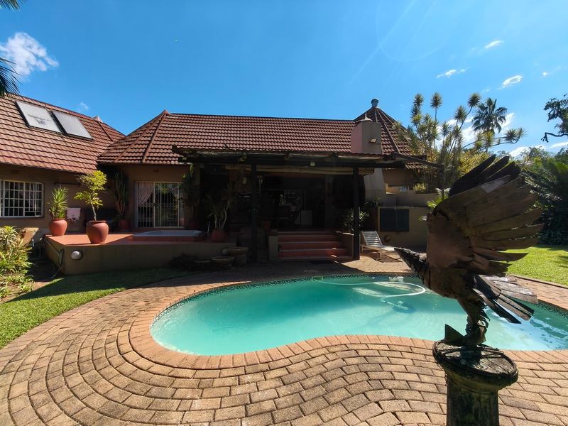 Rear view of the property featuring a swimming pool, paved surround, and a covered patio area with tiled steps.