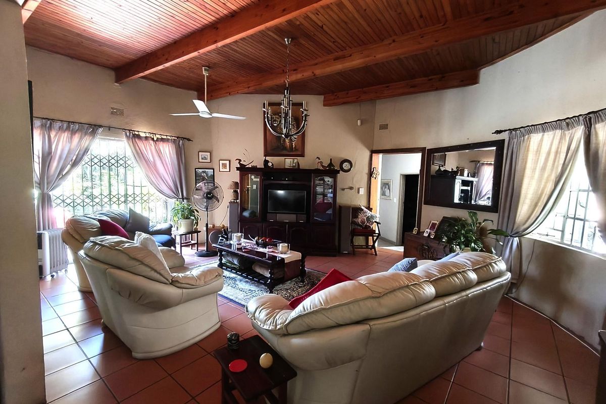 Spacious living room featuring a high vaulted timber ceiling, exposed wooden beams, and terracotta floor tiles, creating a warm and rustic atmosphere.
