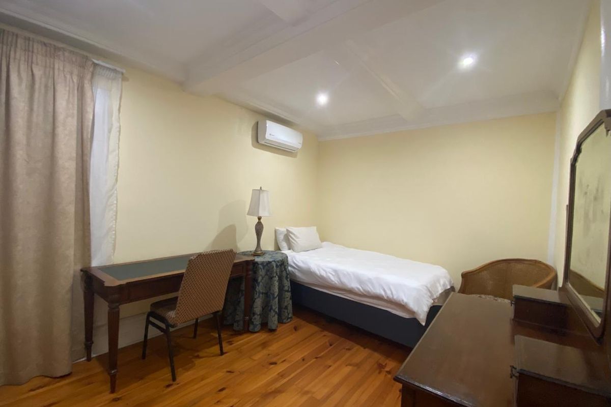 A bedroom featuring polished timber flooring, recessed ceiling lighting, and a wall-mounted air conditioning unit.