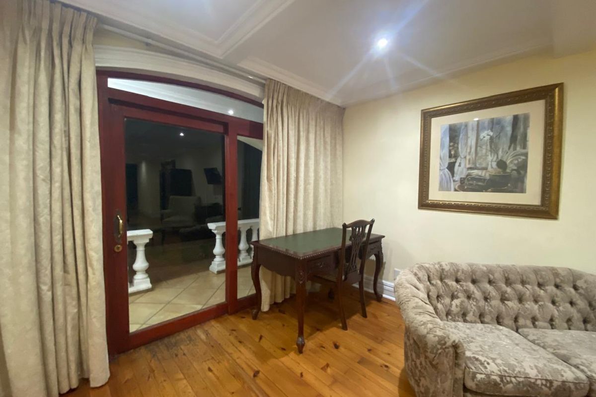 A living area featuring polished timber flooring, crown molding, and a large sliding door providing access to an outdoor balcony space.