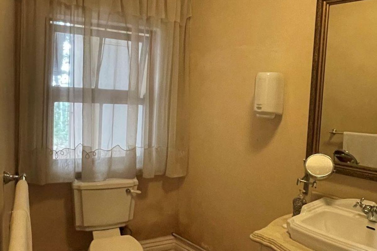 A functional bathroom featuring a vanity with a basin, a toilet, and timber flooring, finished with classic crown molding.