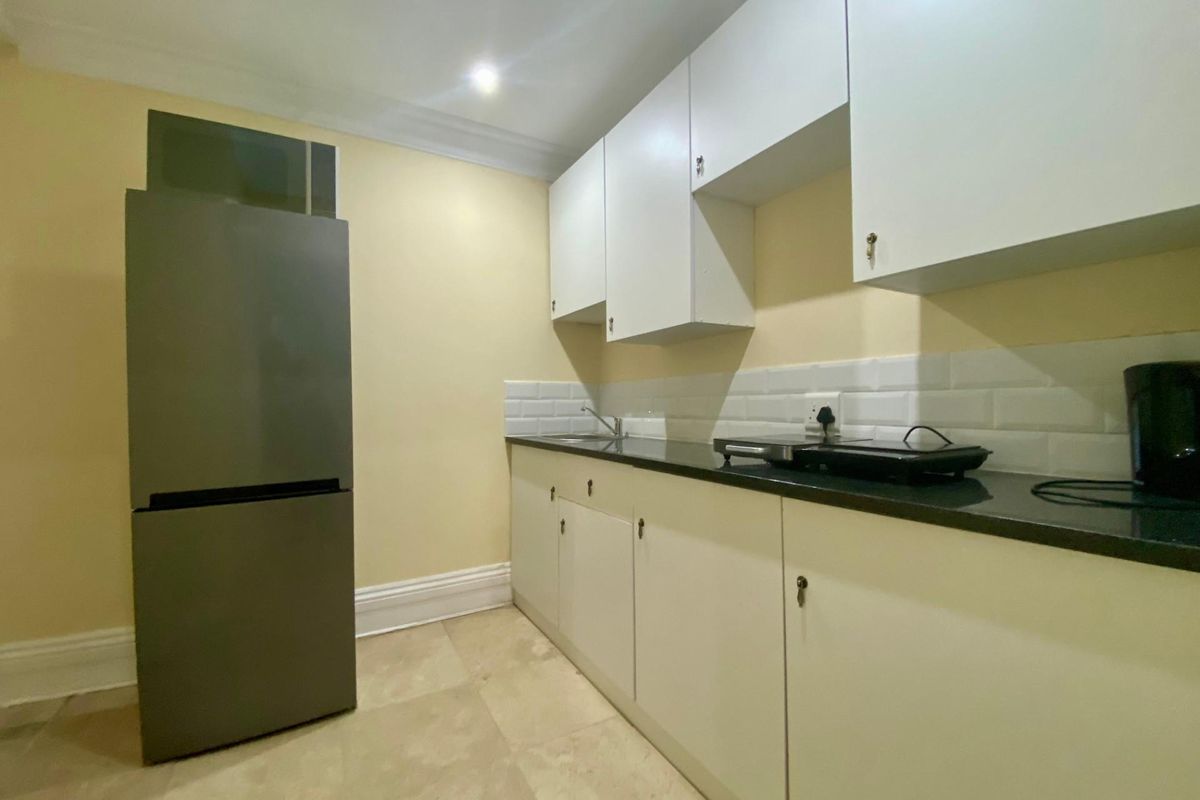 A compact kitchen featuring white cabinetry, dark countertops, and a subway tile backsplash, providing a functional workspace for an apartment.