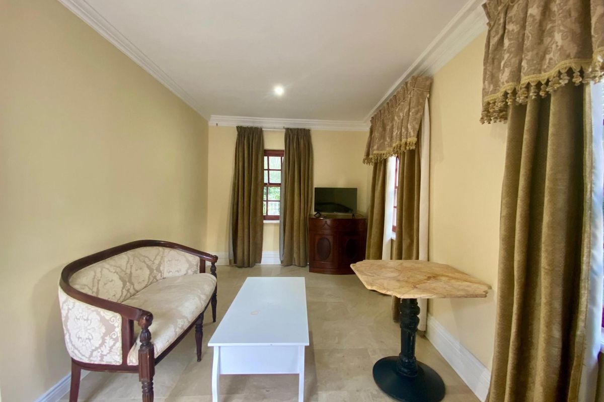 A living room featuring neutral tiled flooring, crown molding, and dual windows with traditional drapery.