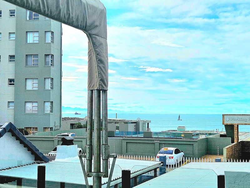 Elevated view overlooking the surrounding residential complex, parking area, and distant ocean horizon.