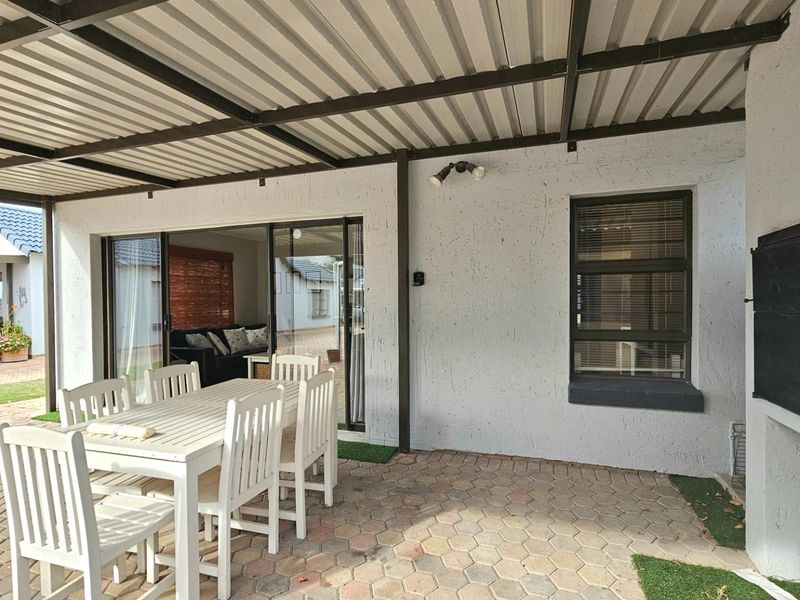 Covered patio area featuring a built-in braai, paved flooring, and sliding door access to the interior living space.