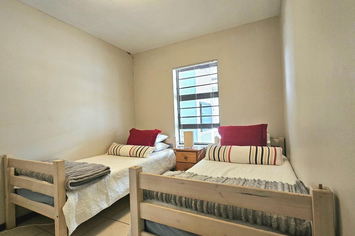 A compact bedroom featuring tiled flooring and a window with fitted blinds, providing natural light.