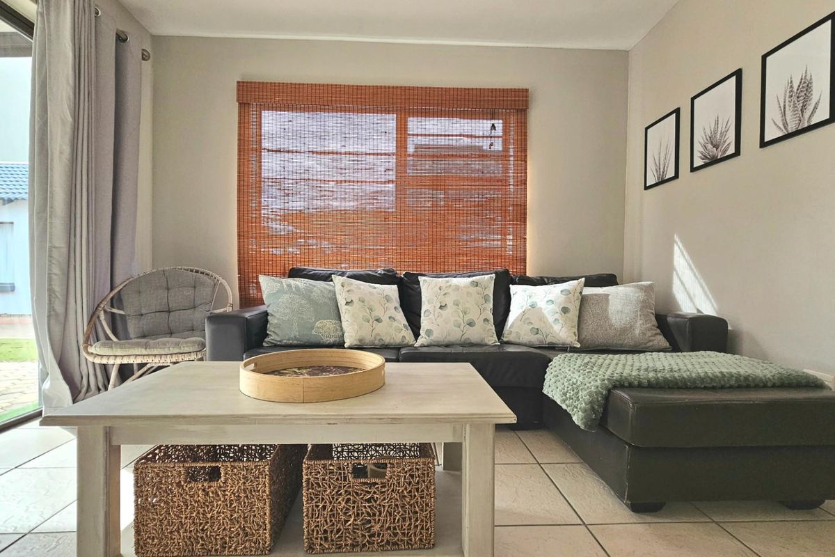 A comfortable living room featuring tiled flooring, large sliding glass doors leading to the patio, and a woven bamboo window blind.