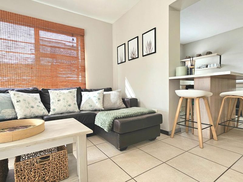 Open plan living area featuring tiled flooring and a breakfast bar counter connecting to the kitchen space.