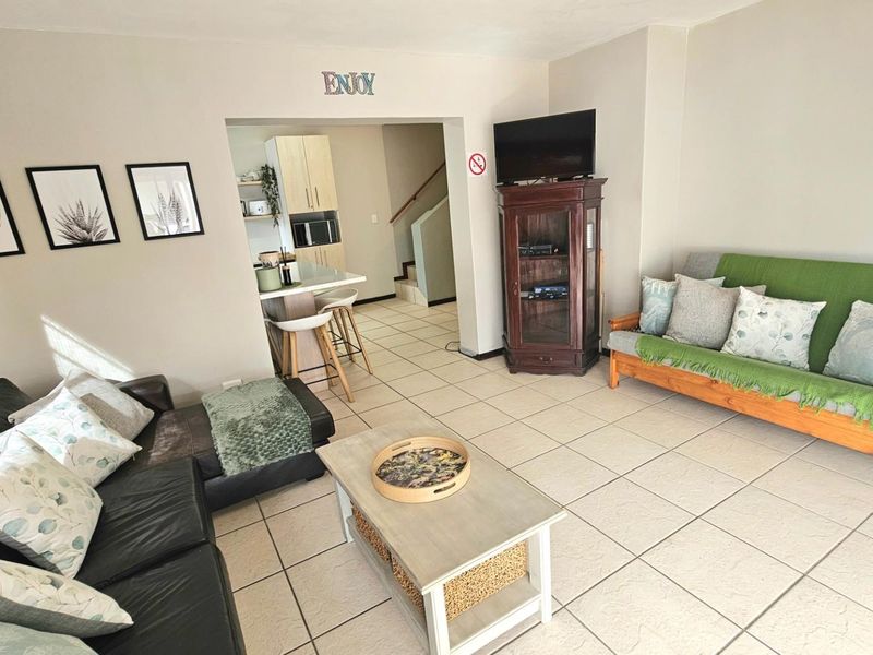 An open-plan living area featuring tiled flooring, neutral walls, and a seamless transition into the adjacent kitchen space.