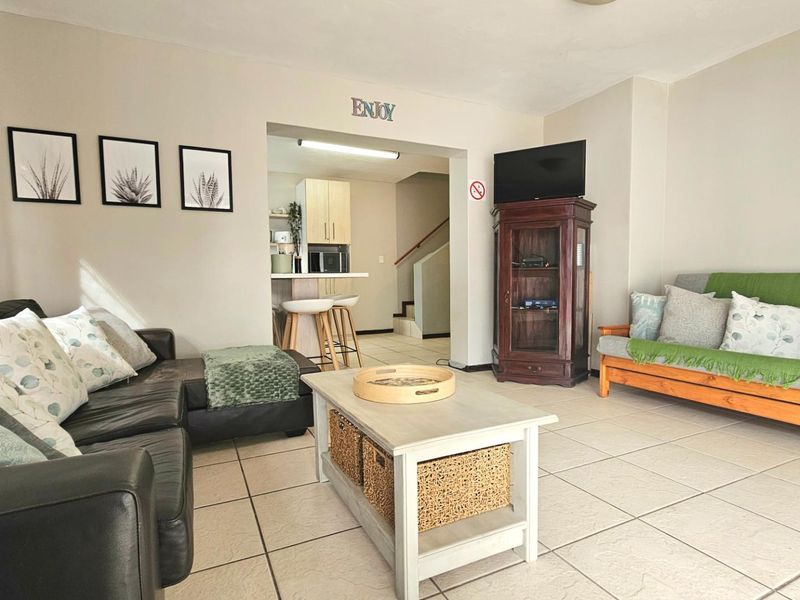 Open plan living area featuring tiled flooring and a view through to the kitchen and staircase area.