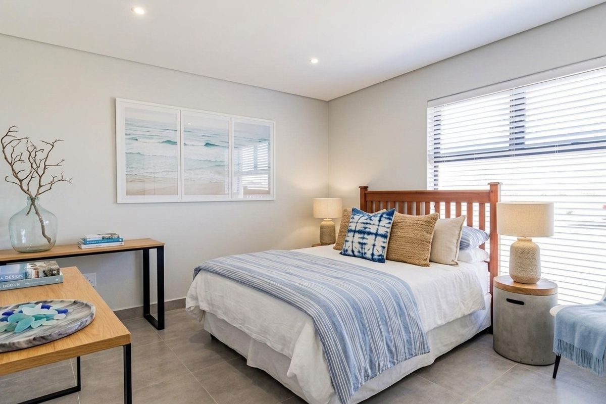 A well-maintained bedroom featuring neutral wall tones, tiled flooring, recessed downlighting, and venetian blinds for adjustable natural light.