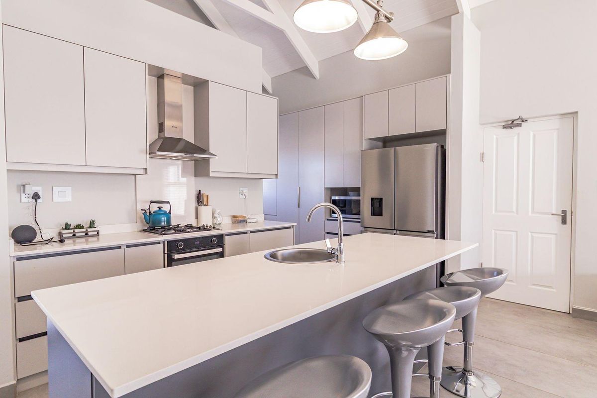 Modern kitchen featuring a central island with sink, sleek cabinetry, gas hob, extractor fan, and vaulted ceilings for an airy, contemporary feel.