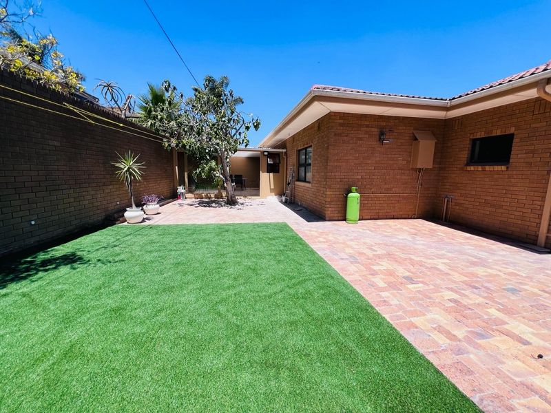 A well-maintained rear courtyard featuring brick paving, artificial lawn, and a brick boundary wall, providing a clean and low-maintenance outdoor space.