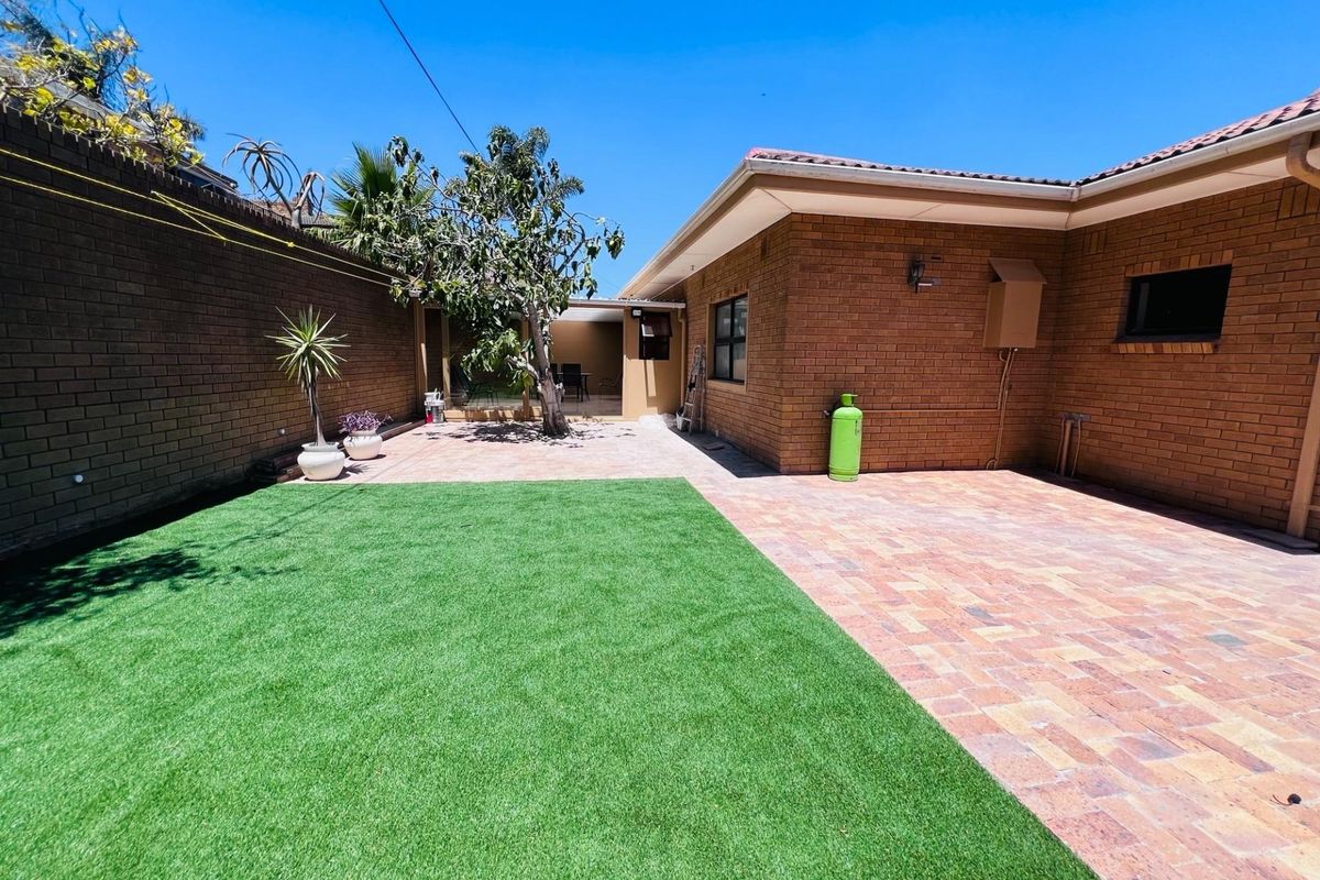 A well-maintained rear courtyard featuring brick paving, artificial lawn, and a brick boundary wall, providing a clean and low-maintenance outdoor space.