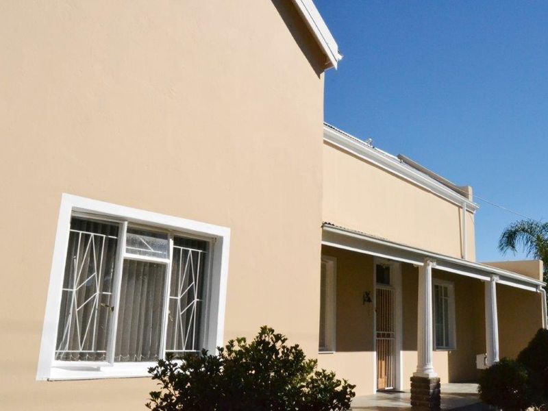 A view of the front facade featuring a covered porch with classic columns, security window bars, and a neutral exterior paint finish.