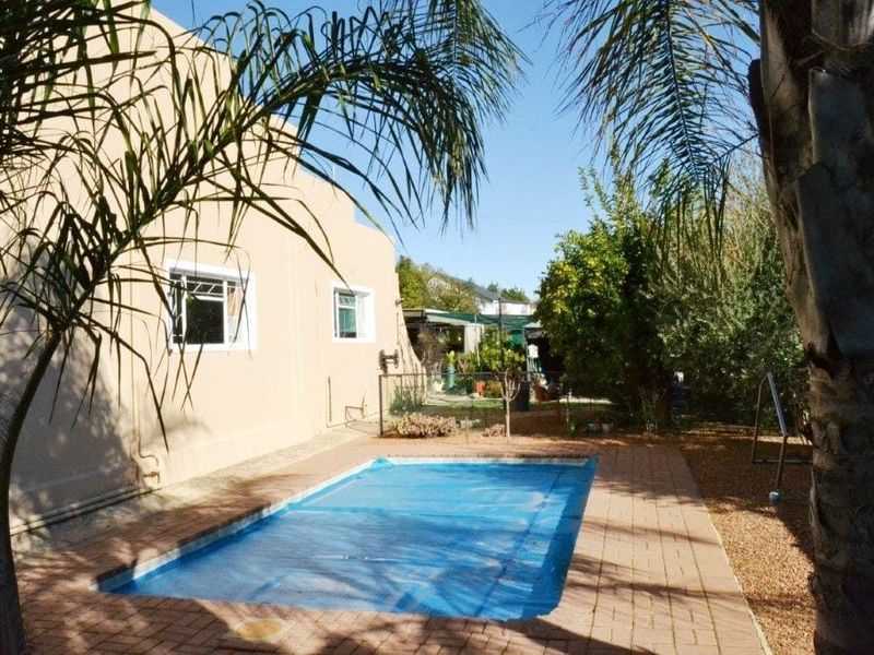 Outdoor pool area featuring a rectangular swimming pool with a paved surround and established garden perimeter.