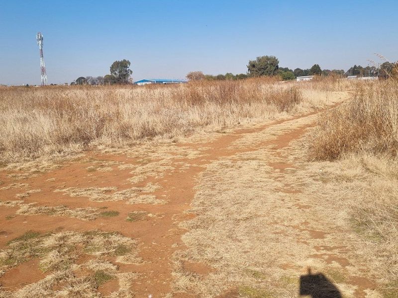 Expansive open farm land featuring natural dry grass and a dirt access track, offering significant potential for development or agricultural use.