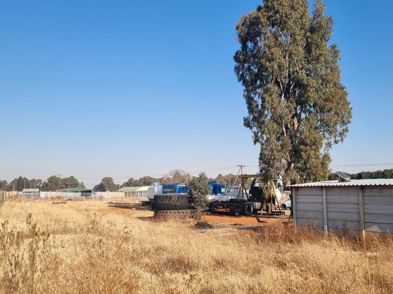 Expansive farm land featuring a precast concrete boundary wall, mature trees, and open field space suitable for agricultural or storage use.