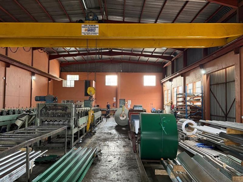 Spacious industrial warehouse featuring a high-clearance ceiling, integrated overhead crane system, and ample floor space for manufacturing or storage operations.