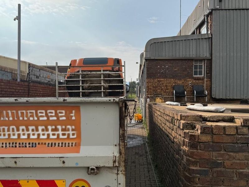 Exterior view of an industrial facility showing a loading bay area with brick retaining walls and metal warehouse cladding.