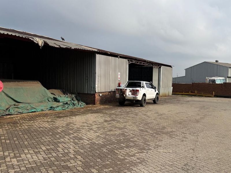 Industrial warehouse facility featuring corrugated metal cladding, open-bay storage areas, and paved yard space suitable for logistics or manufacturing operations.