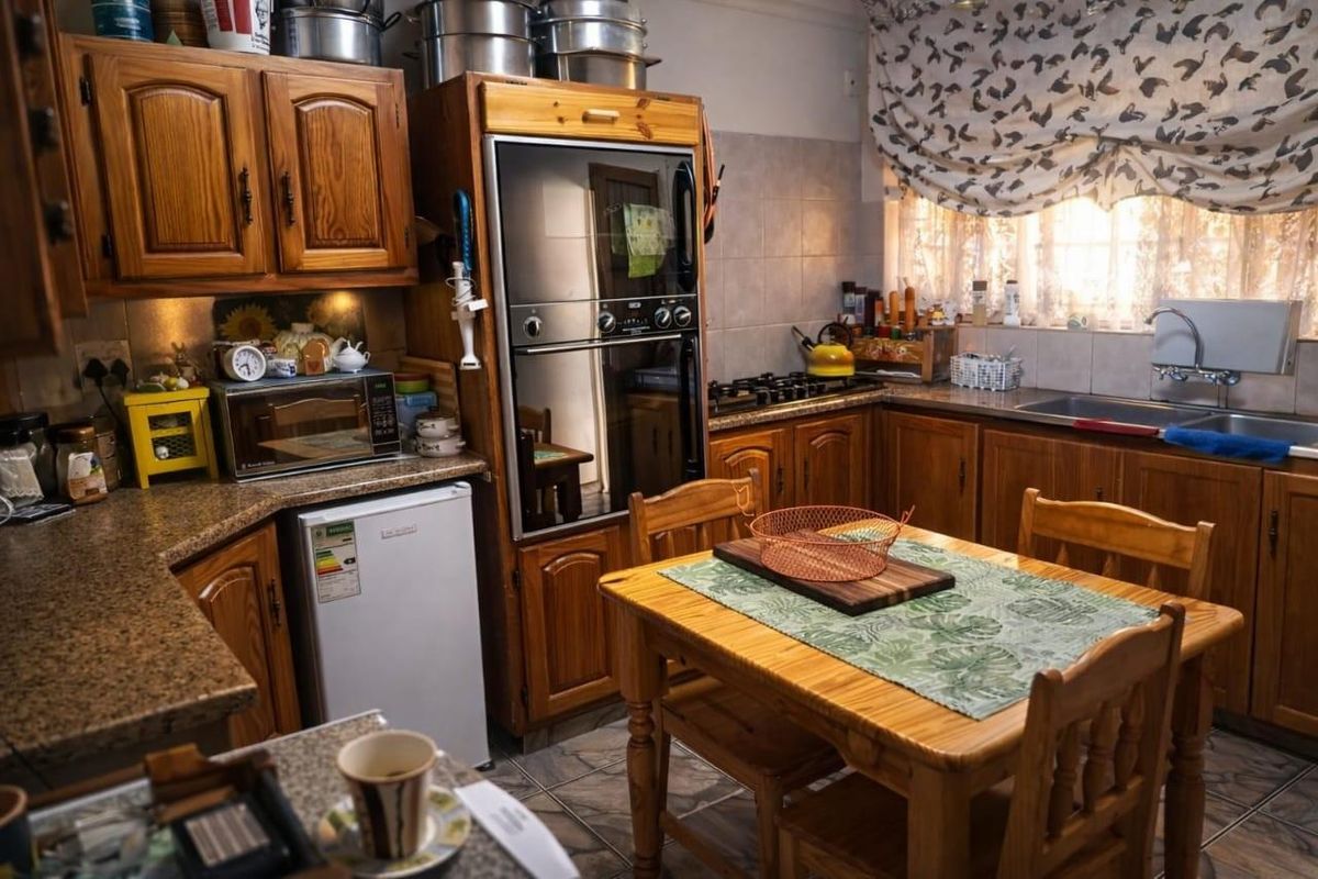 A functional kitchen featuring traditional wooden cabinetry, granite countertops, a built-in oven, and a gas hob with tiled finishes throughout.