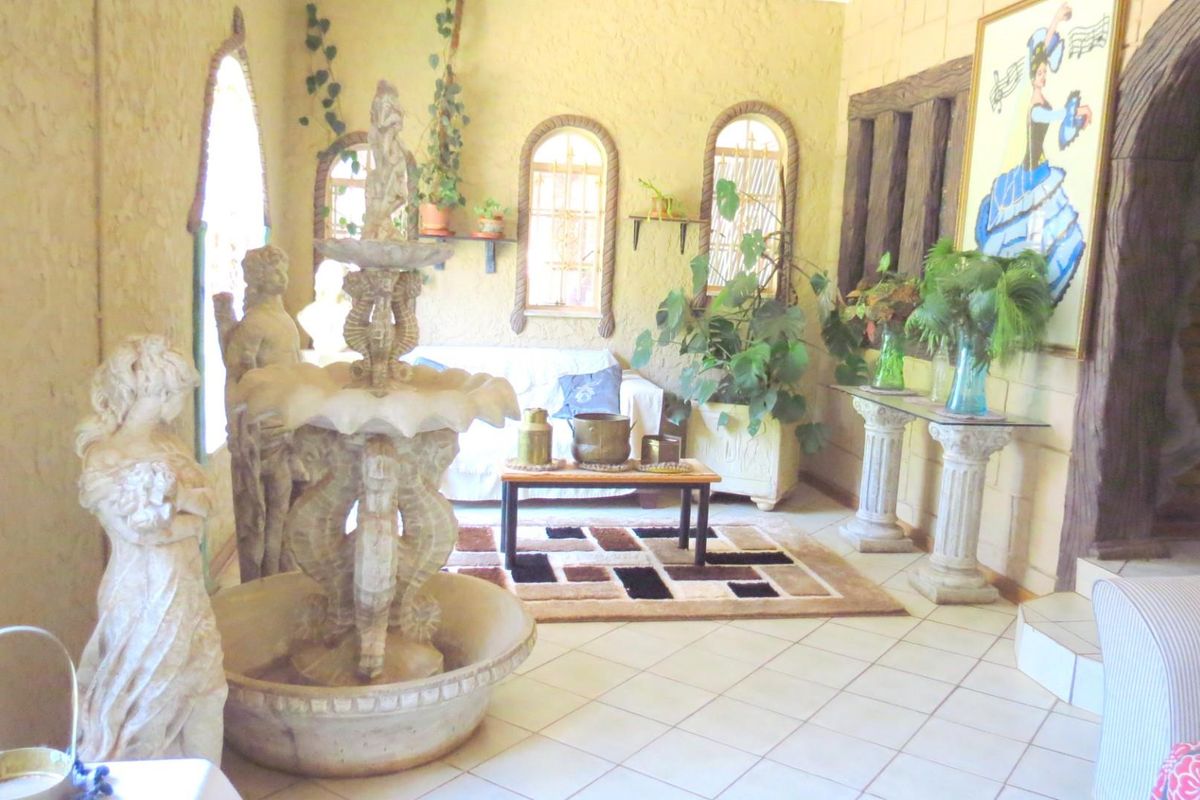 A unique interior living space featuring textured walls, arched window frames, and a central decorative stone fountain feature.