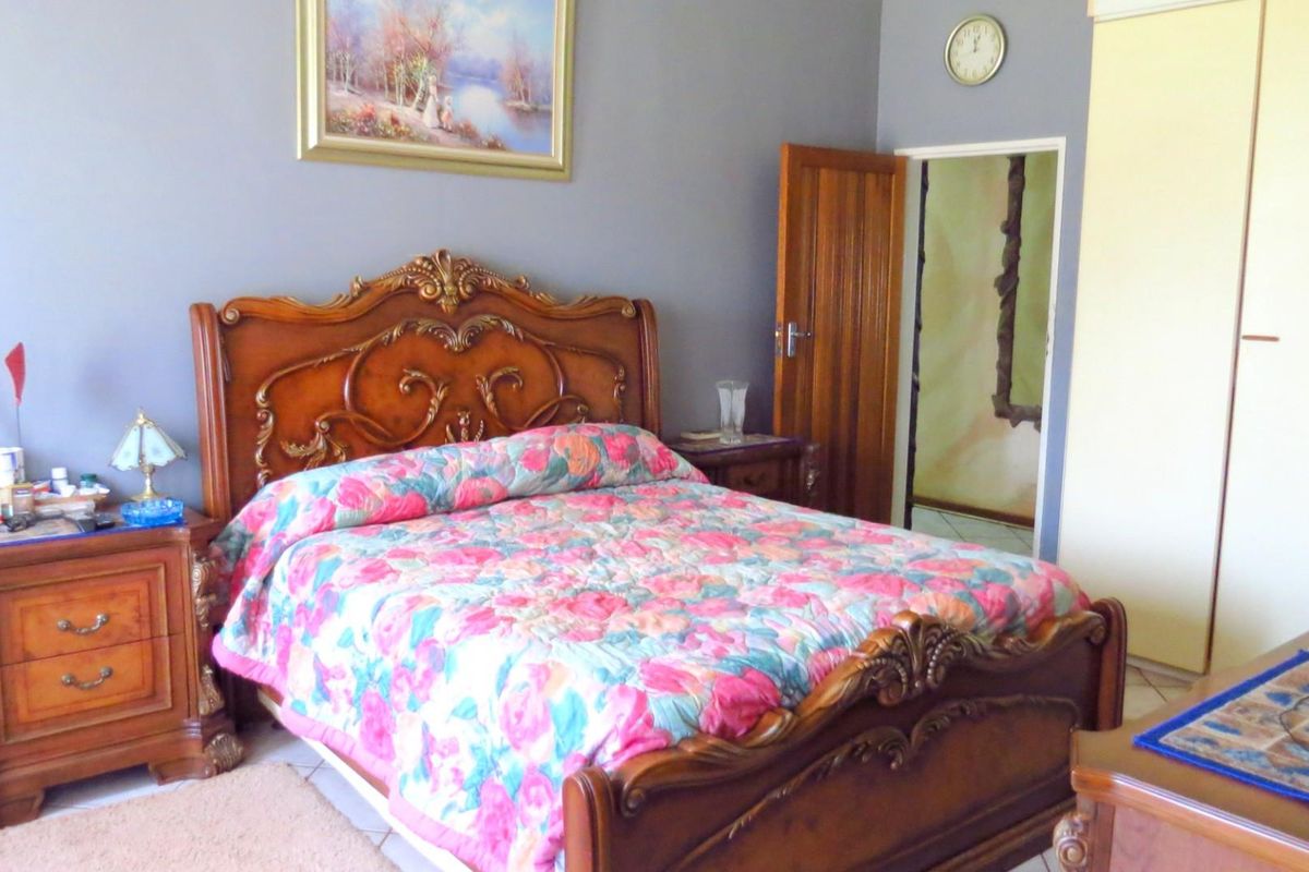 A bedroom featuring tiled flooring, built-in cupboards, and a wooden door leading to an adjacent space.