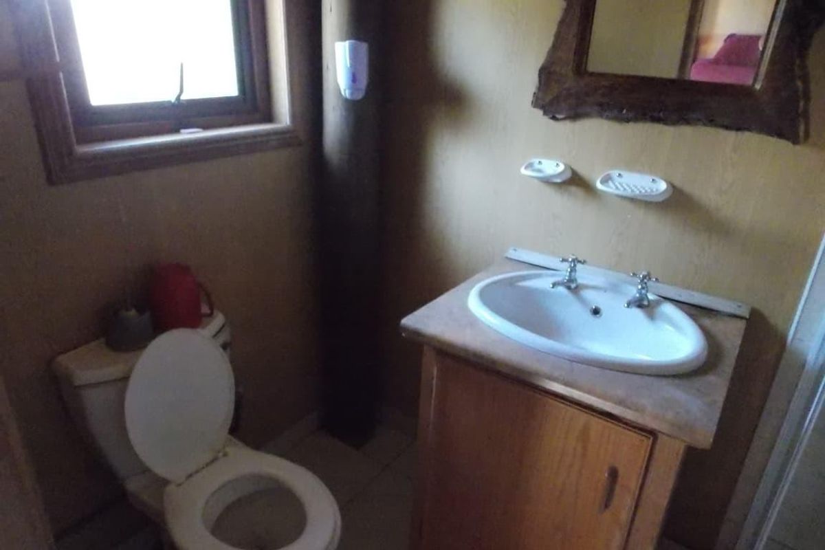 A compact bathroom featuring a vanity with a drop-in basin, a standard toilet, and a window, reflecting a dated and functional design.