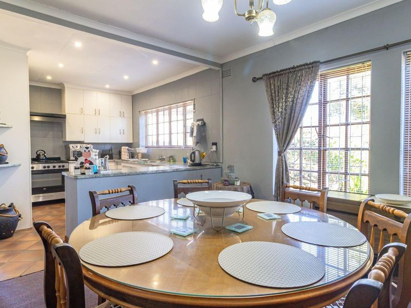 Open-plan dining area flowing into a functional kitchen featuring built-in cabinetry, granite countertops, and a gas stove.
