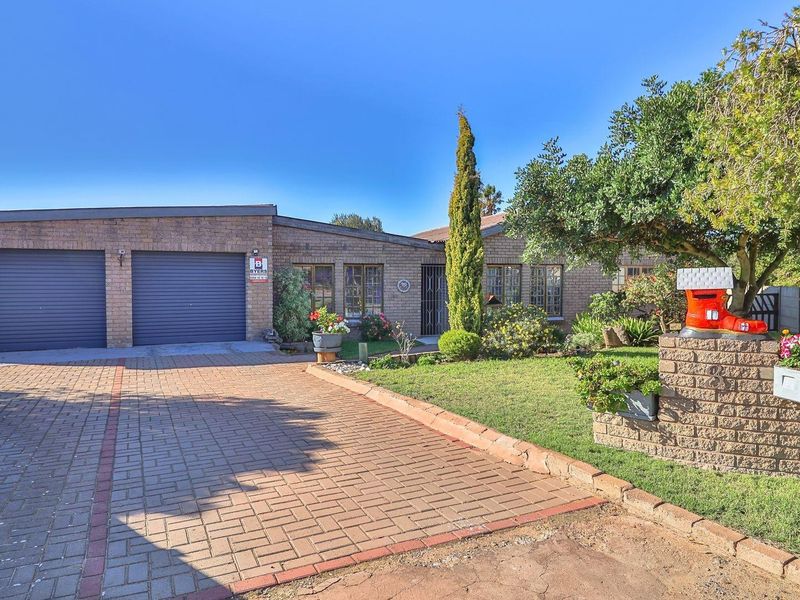 Front exterior view of a brick-faced house featuring a double garage, paved driveway, and established front garden with a decorative mailbox.