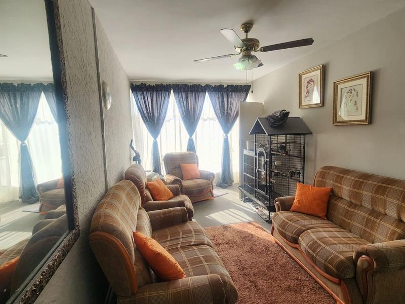 A living room featuring a ceiling fan and large windows with curtains, providing natural light to the space.