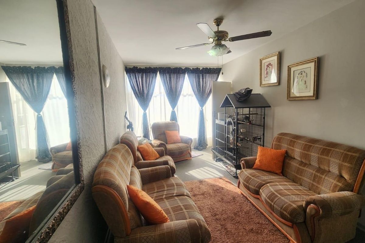 A living room featuring a ceiling fan and large windows with curtains, providing natural light to the space.