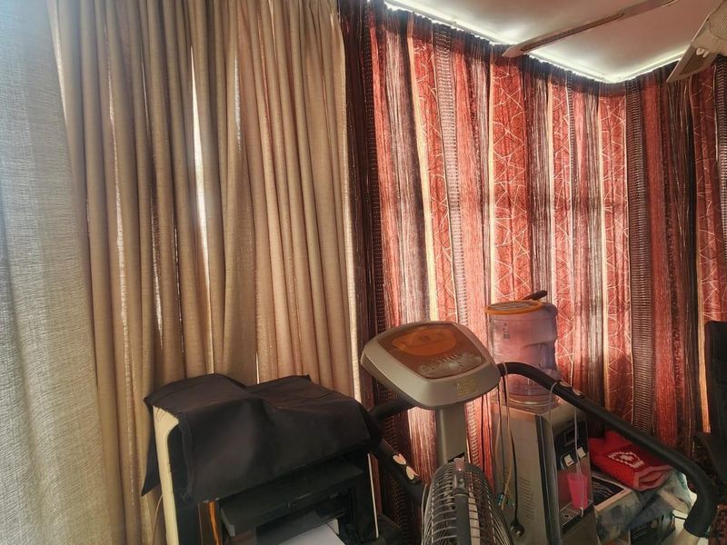 A sunroom or enclosed patio area featuring floor-to-ceiling curtains and a painted brick wall finish.
