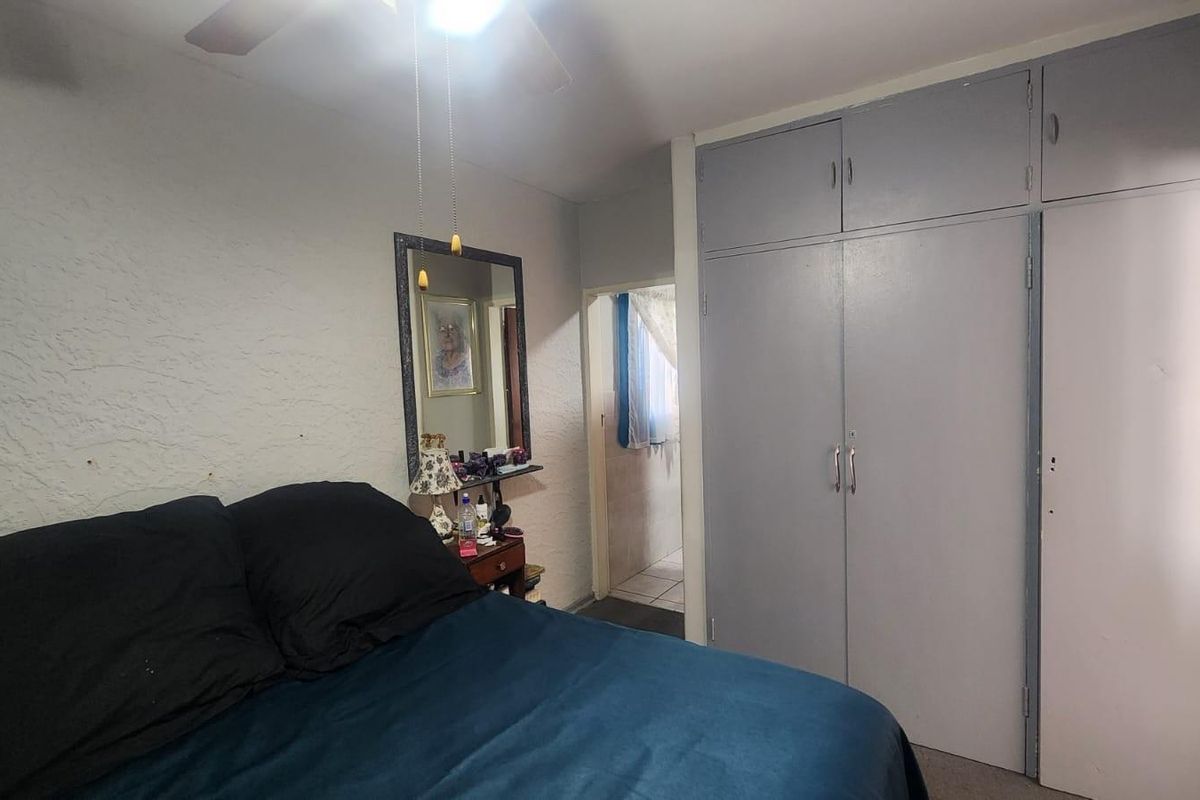 A bedroom featuring built-in cupboards with overhead storage and a ceiling fan, providing functional storage space.