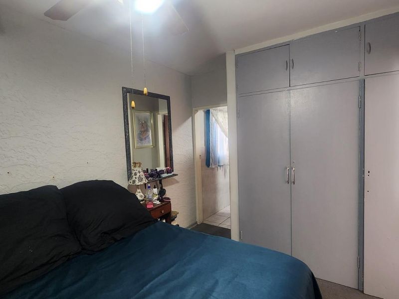 A bedroom featuring built-in cupboards with overhead storage and a ceiling fan, providing functional storage space.