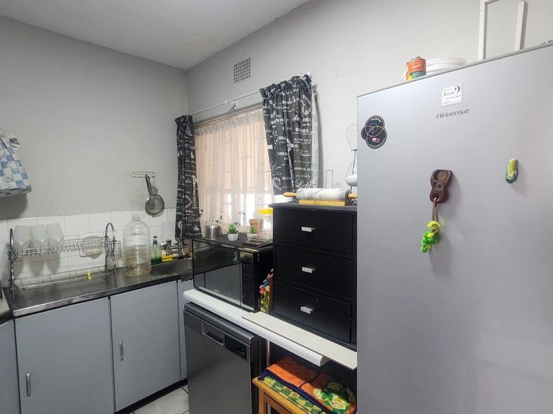A functional kitchen featuring grey cabinetry, a stainless steel sink, and tiled splashback, providing a practical workspace for daily meal preparation.