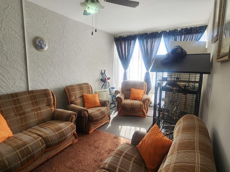 A living room featuring textured wall finishes, carpet flooring, and a ceiling fan, providing a functional space for relaxation.