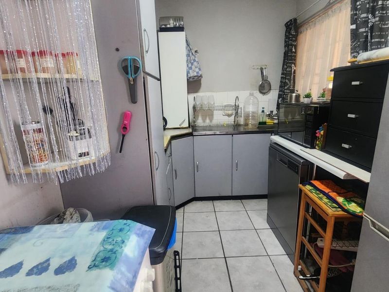 A compact kitchen featuring grey cabinetry, tiled flooring, and a stainless steel sink, providing a functional workspace within the apartment.
