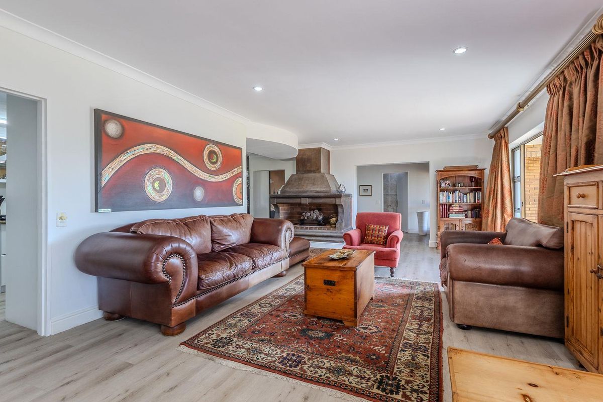 Spacious living room featuring a prominent built-in stone fireplace, recessed downlighting, and light-toned wood-look flooring.
