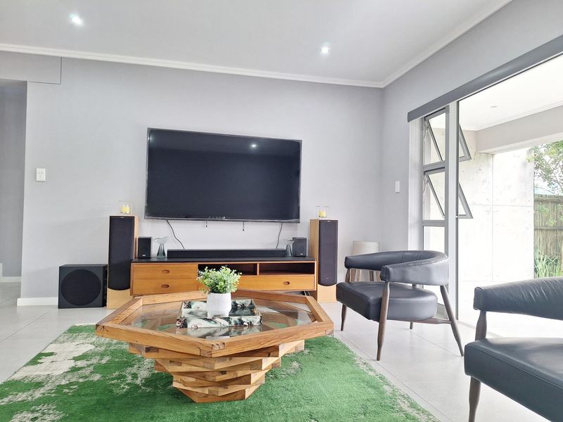 A bright and modern living room featuring tiled flooring, recessed downlights, and large aluminium-framed sliding doors providing access to the outdoor area.